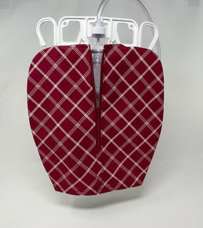 Red and white plaid cotton fabric cover with matching red zipper fitted over a 2000 ml volume catheter bag.  The bag shown with the cover on it has a two hanger apparatus that is fully usable as the front zip cover is on the bag.